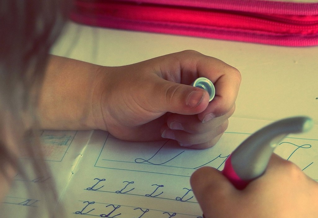 Barn gör läxa, skriver bokstäver i en bok.
